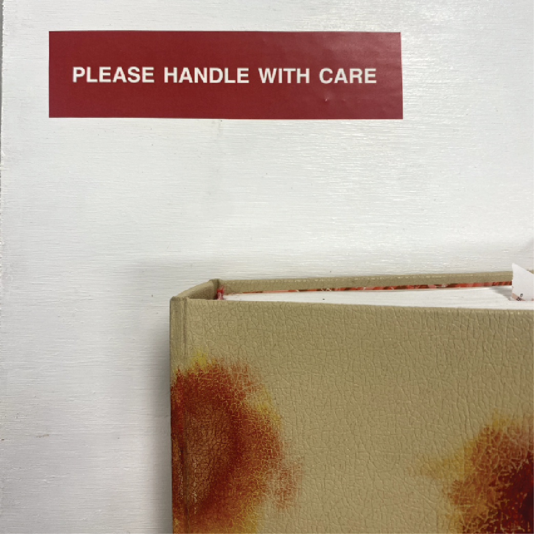 corner of a book on white backround with a red tag saying 'please handle with care' on the top left corner