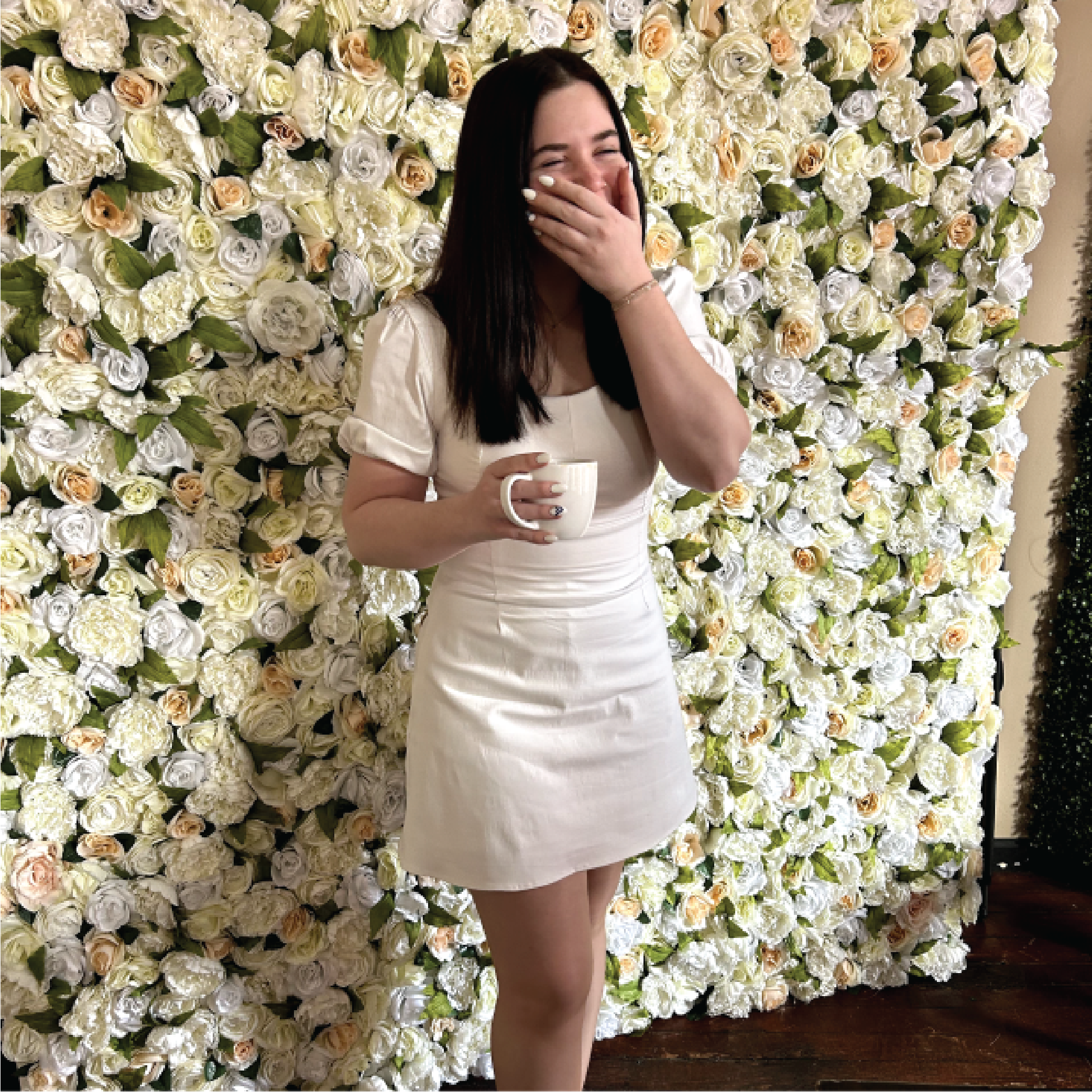 Kieah standing and laughing in front of a floral wall